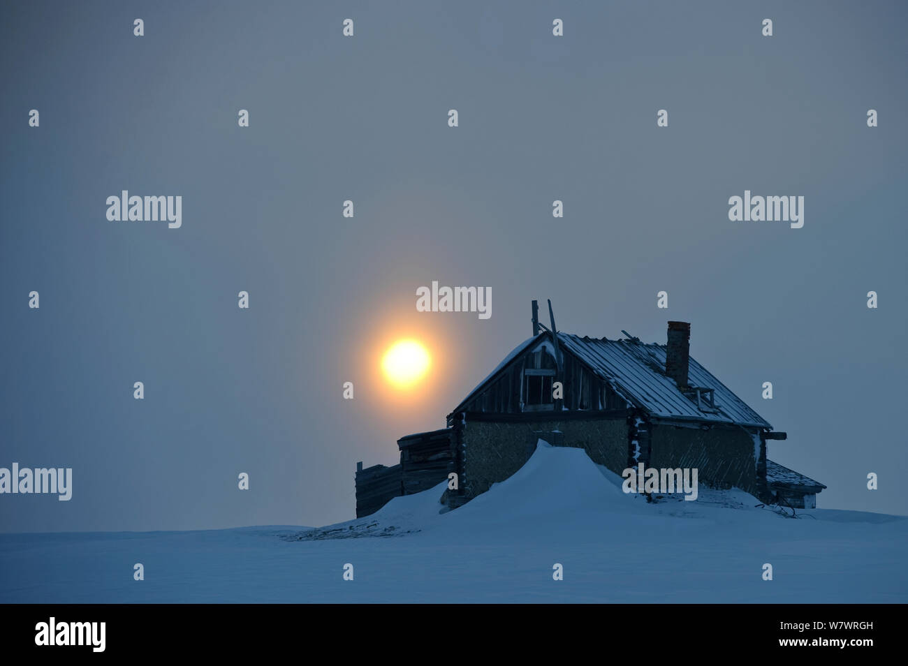 Old house covered in snow with setting sun, Wrangel Island, Far Eastern Russia, March 2011. Stock Photo