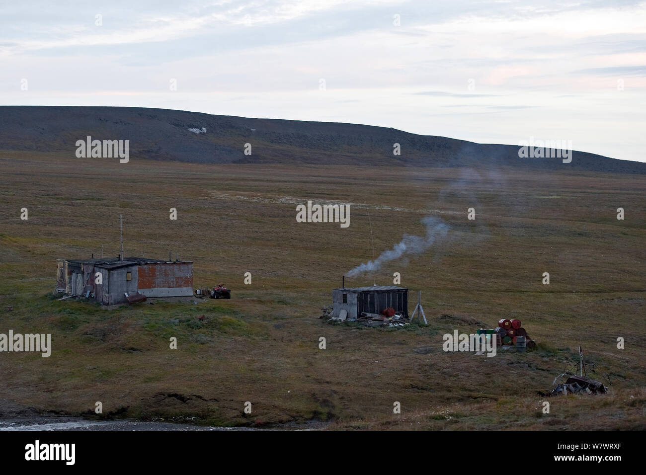 House with smoke coming from chimney in landscape at Wrangel Island, Far Eastern Russia. August 2010. Stock Photo