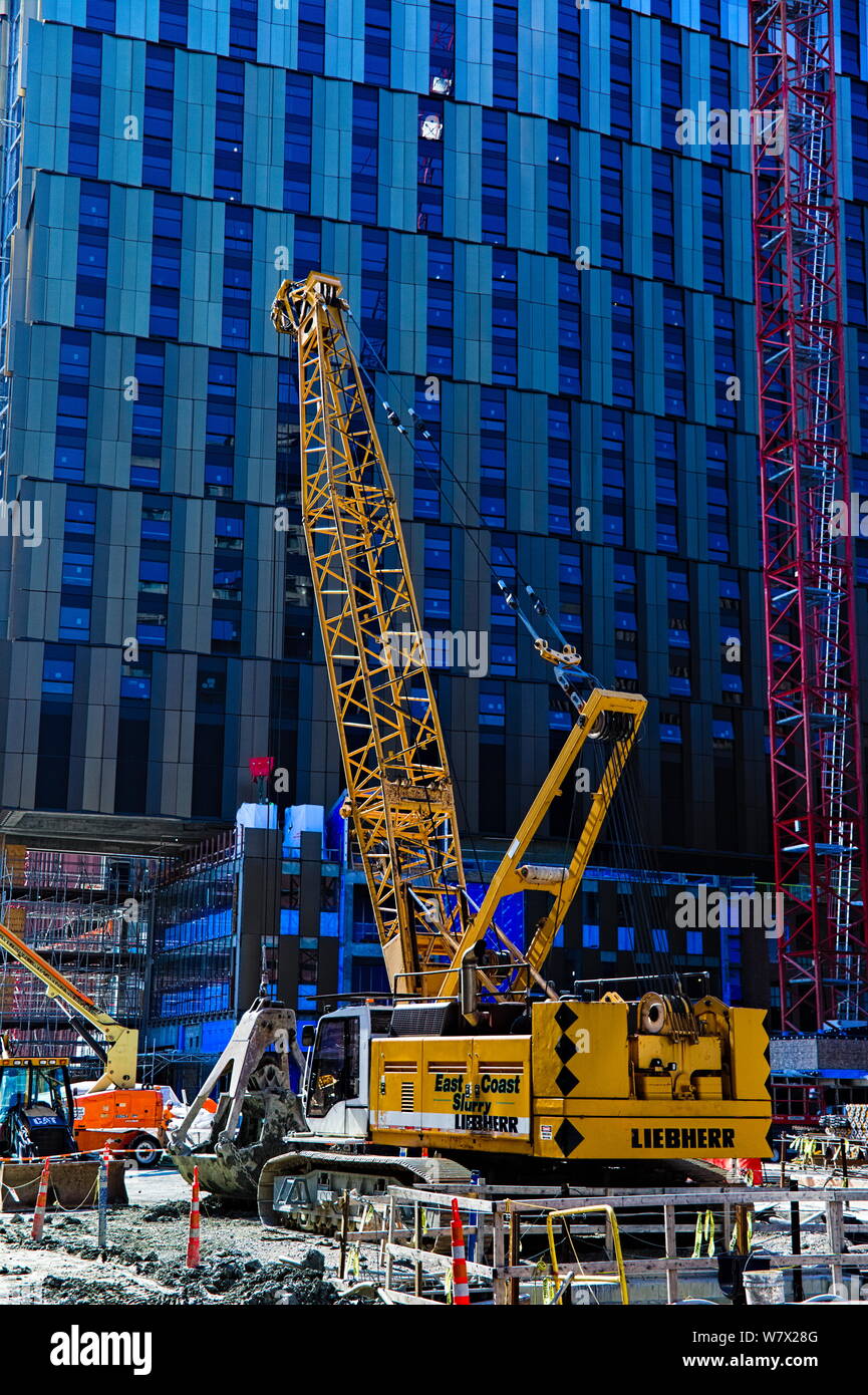 A crane with a clamshell bucket sits parked at a construction site in Kendall Square, Cambridge, Massachusetts. Stock Photo