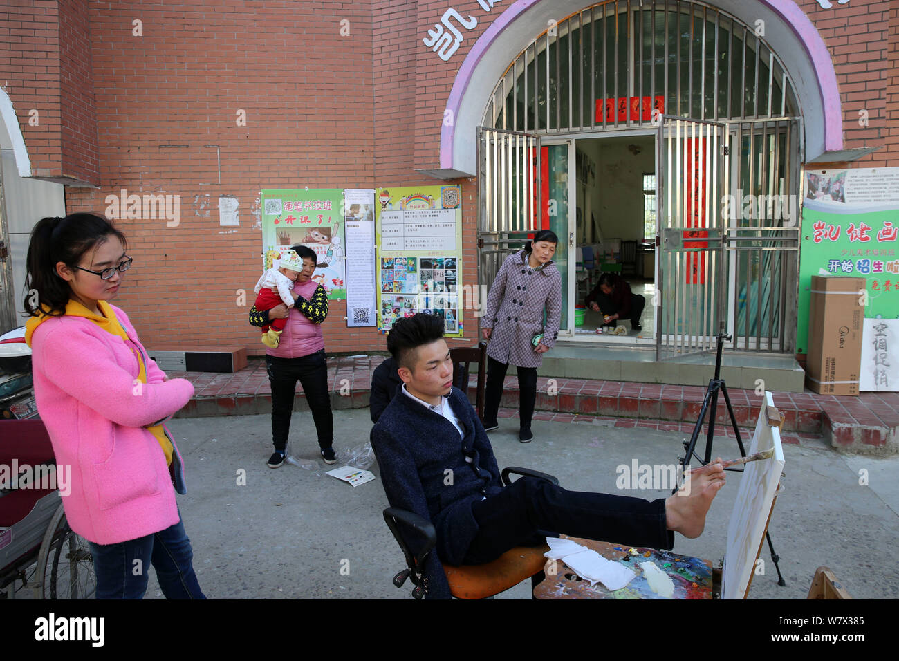 People watch handicapped Chinese painter Liu Kaijian drawing a picture by his talented toes at his studio in Nantong city, east China's Jiangsu provin Stock Photo