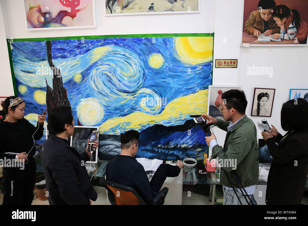 People take photos of handicapped Chinese painter Liu Kaijian drawing a picture by his talented toes at his studio in Nantong city, east China's Jiang Stock Photo