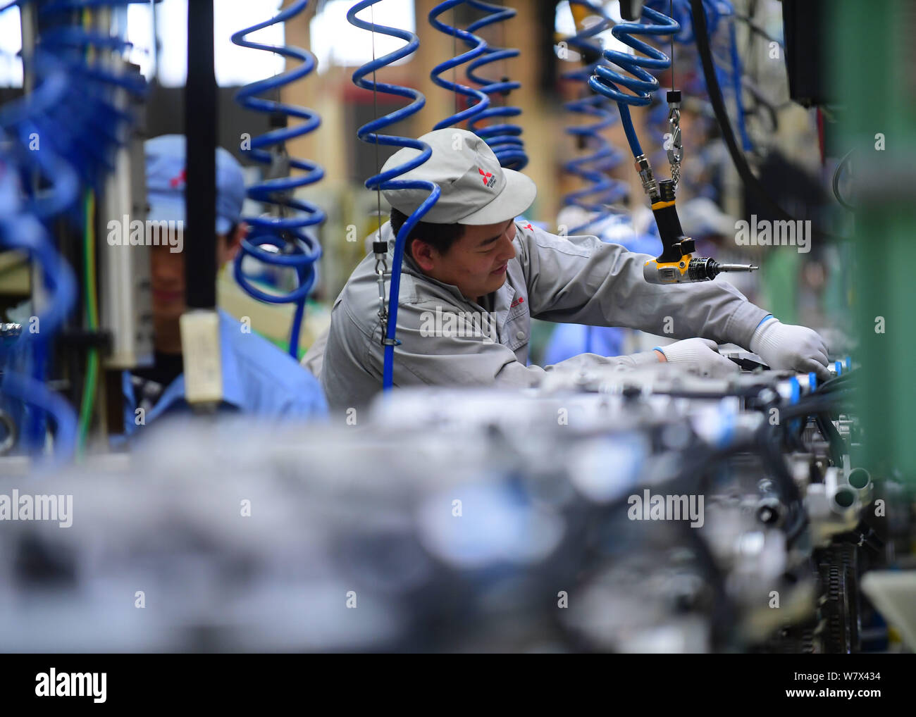 --FILE--A Chinese worker assembles engines on the assembly line at an ...