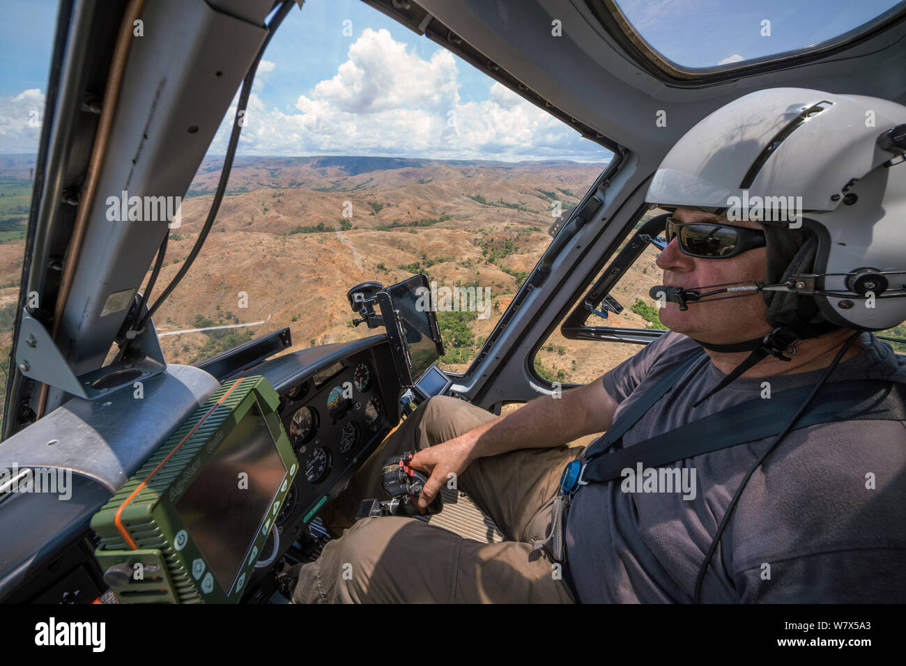Food and Agriculture Organization (FAO) helicopter pilot Eric Gadot, an expert at locust control operations flying over effected area, near Miandrivazo, Madagascar. December 2013. Stock Photo