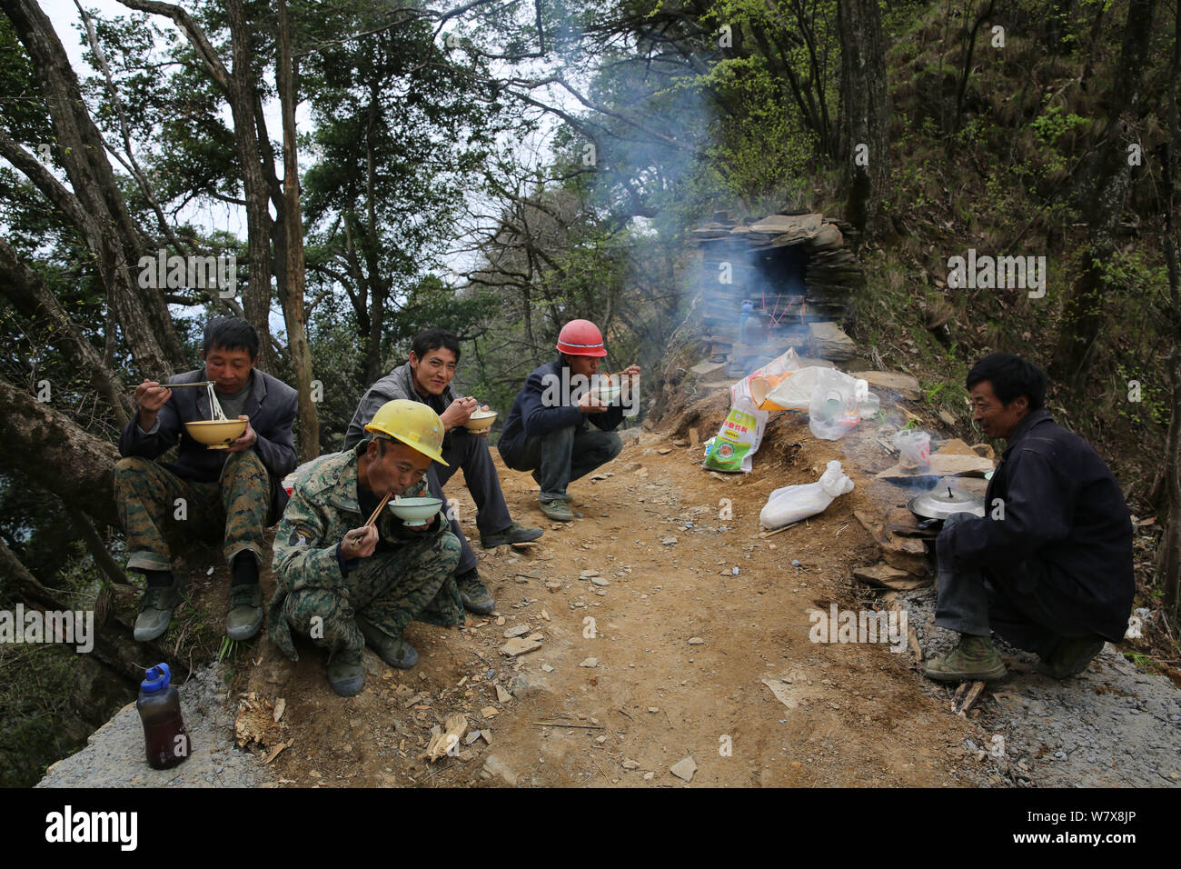 Chinese villagers eat noodles together when they use 10 mules to transport construction materials for building a mountain walkway on Yunwu Mountain in Stock Photo