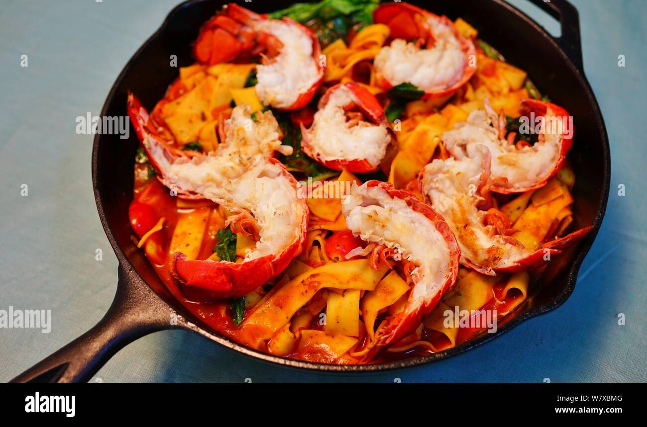 Dish of fresh pasta with lobster in the shell, tomato sauce and sautéed ...