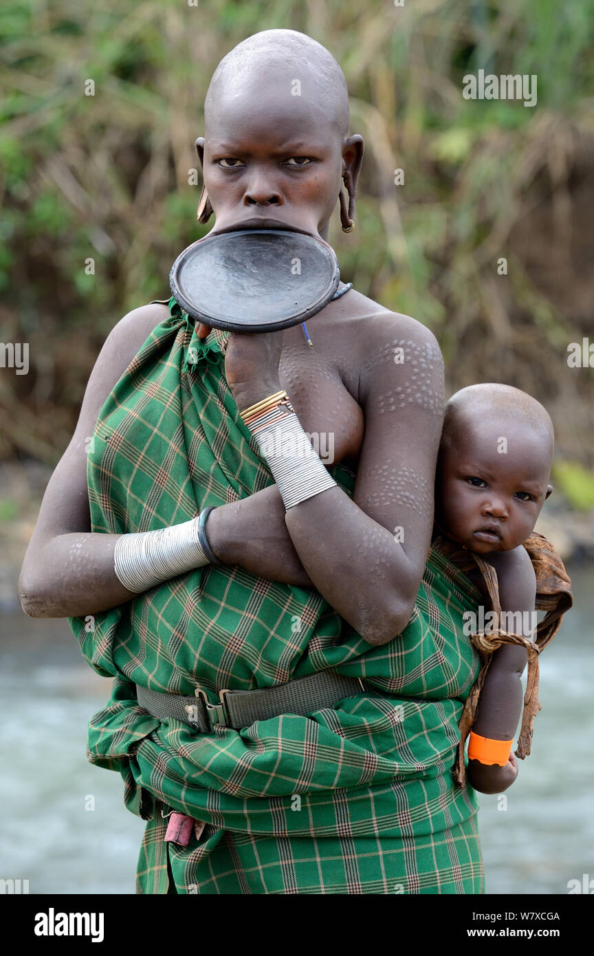 Portrait of Suri / Surma woman wearing lip plate and carrying her baby. Omo river Valley, Ethiopia, September 2014. Stock Photo