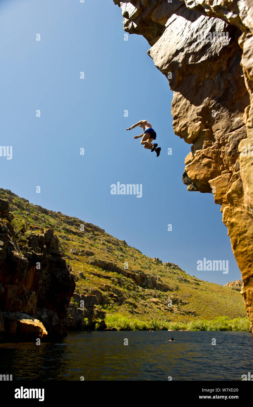 Man jumping from a cliff into the Twee River to cool down during mid-summer. The Twee River is home to the critically endangered Twee River redfin (Barbus erubescens). Koue Bokkeveld / Cedarberg region, Western Cape, South Africa. February 2014. Stock Photo