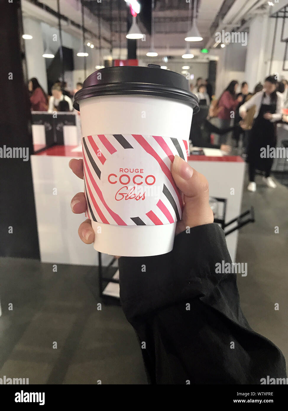A trendy Chinese girl shows a cup of coffee she bought from the Coco Chanel  Cafe on West Nanjing Road in Shanghai, China, 12 April 2017. Chanel is h  Stock Photo - Alamy