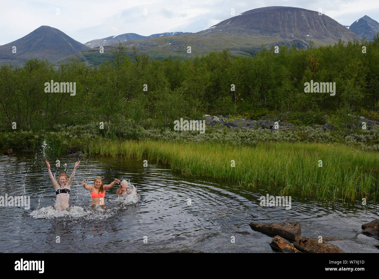 Woman and two teenage girls splashing in river on hiking trip, Laponia Circuit, along the Padjelantaleden trail, Padjelanta National Park and Sarek National Park, Norrbotten, Lapland, Sweden. Model released Stock Photo