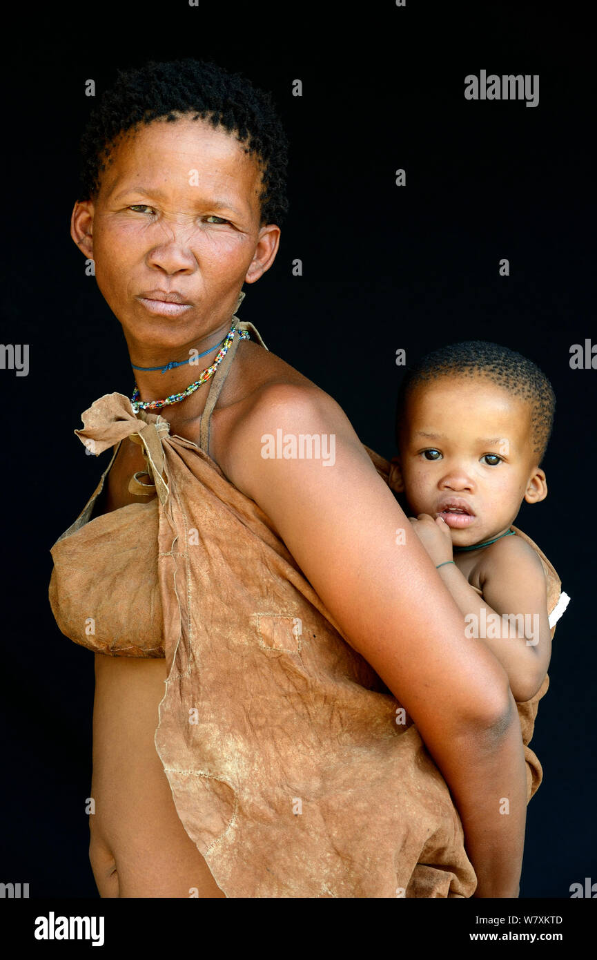 Portrait of Naro San woman with baby, wearing traditional duiker leather clothing, Kalahari, Ghanzi region, Botswana, Africa. October 2014. Stock Photo