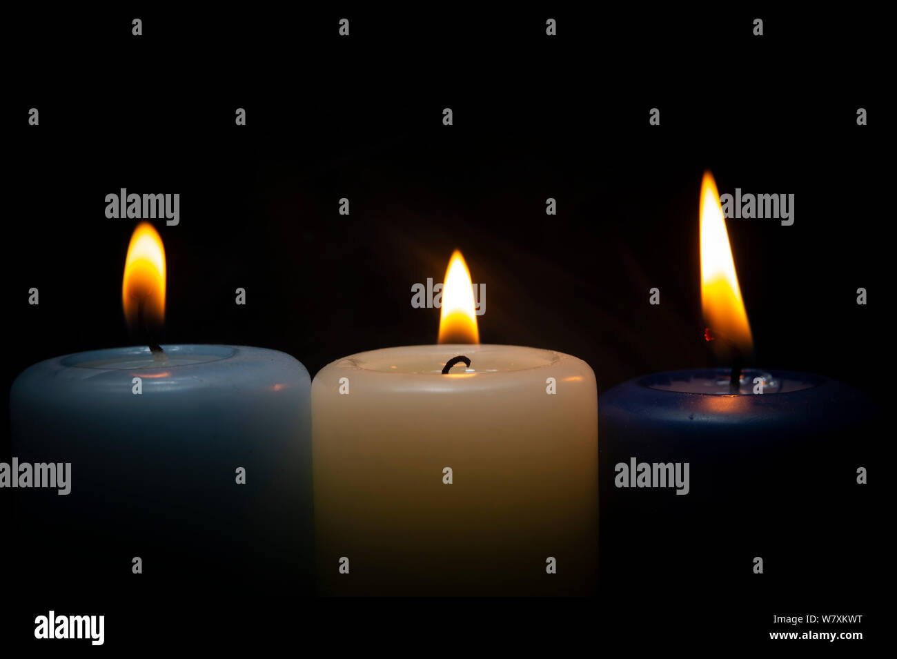 Close up of three colorful wax candles flame on a dark background with ...