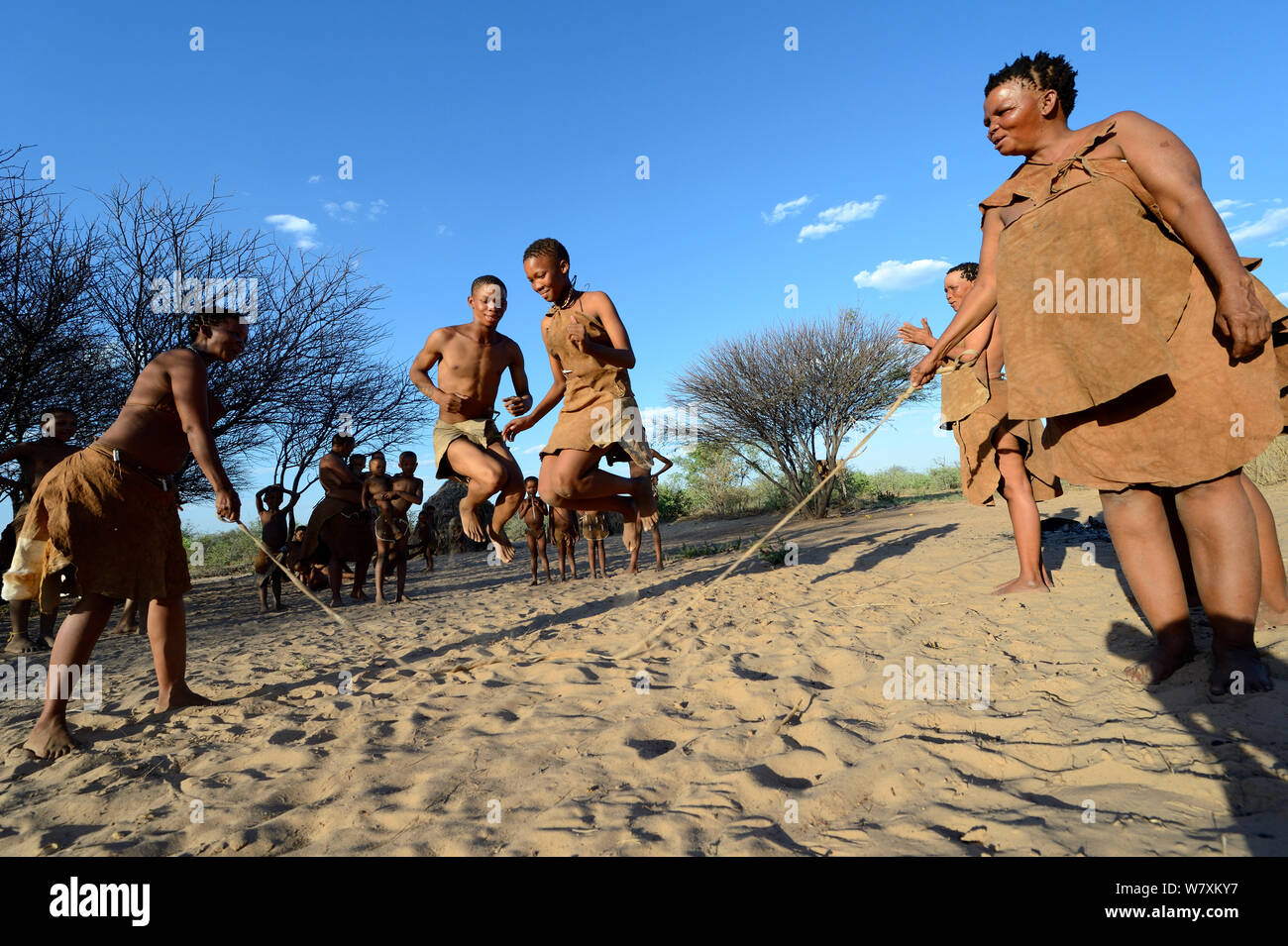 Naro San Bushmen family, women and children playing with skipping rope, Kalahari, Ghanzi region, Botswana, Africa. Dry season, October 2014. Stock Photo