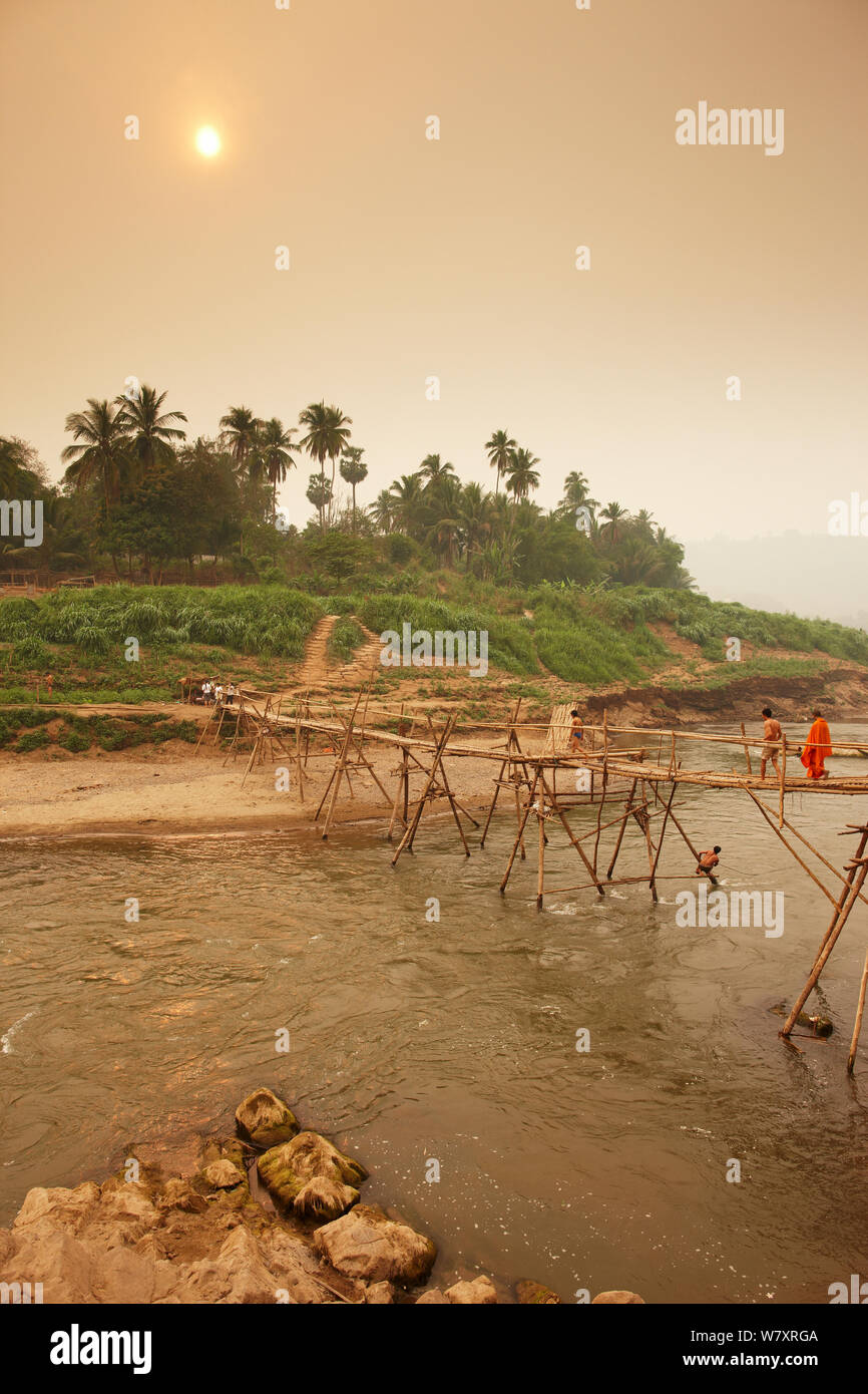 People crossing a footbridge over the Nam Khan River, Luang Prabang, Laos, March 2009. Stock Photo