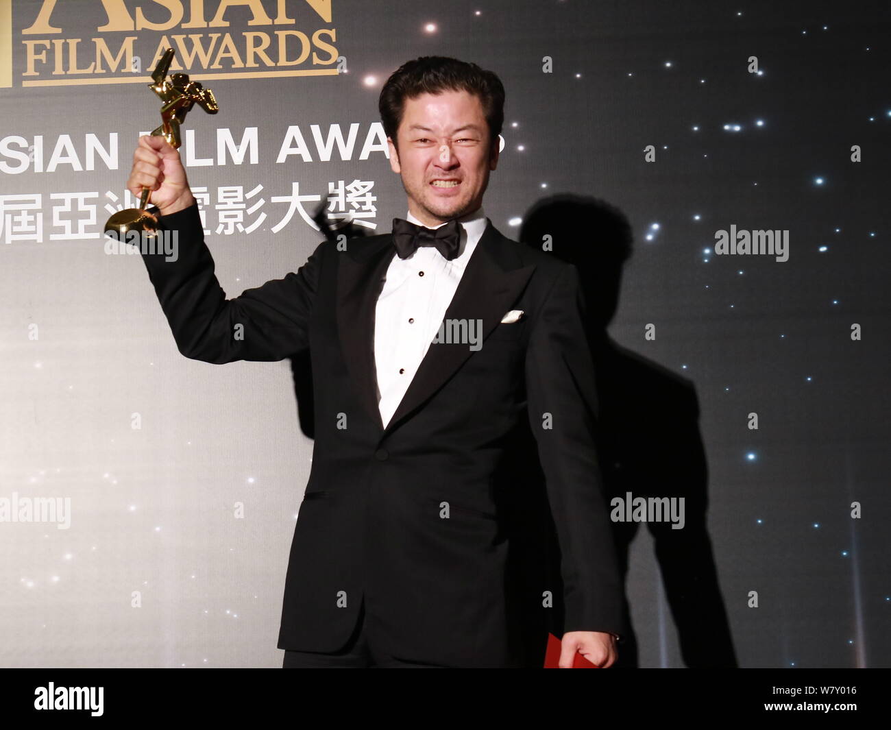 Japanese actor Tadanobu Asano holds up his trophy after winning the