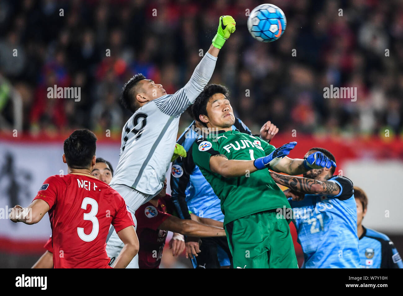 Goalkeeper Zeng Cheng of China's Guangzhou Evergrande F.C., second left, hits the ball over goalkeeper Jung Sung-ryong, center, and other players of J Stock Photo