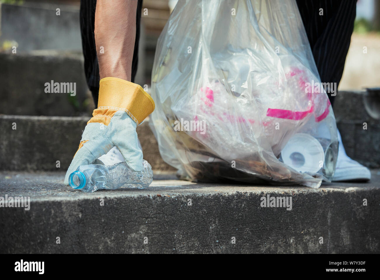A close-up of an unrecognizable person picking up litter on the streets. Stock Photo