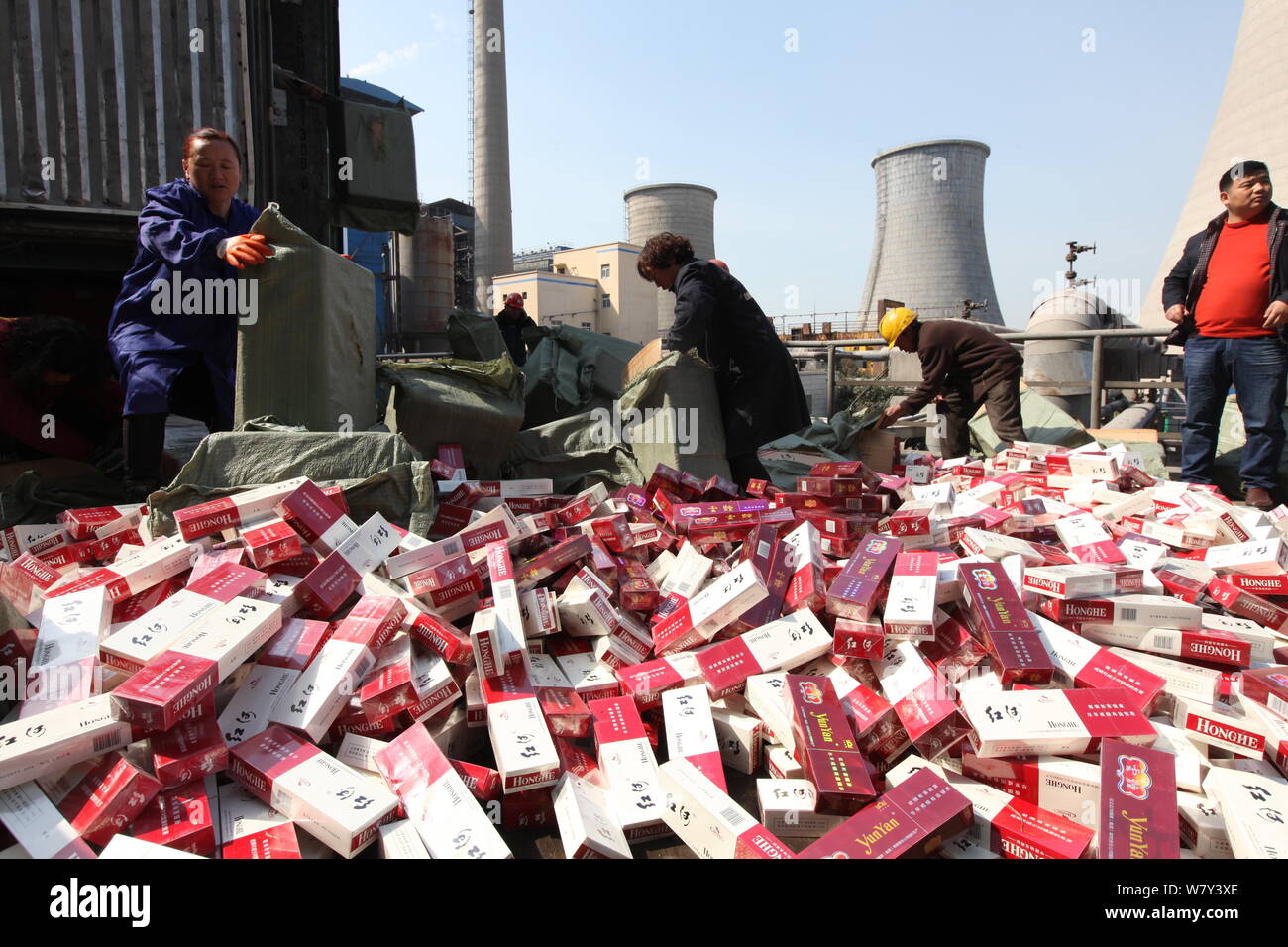 Chinese employees pour the fake-brand and inferior cigarettes to be destoryed at a thermal power plant in Xuchang city, central China's Henan province Stock Photo