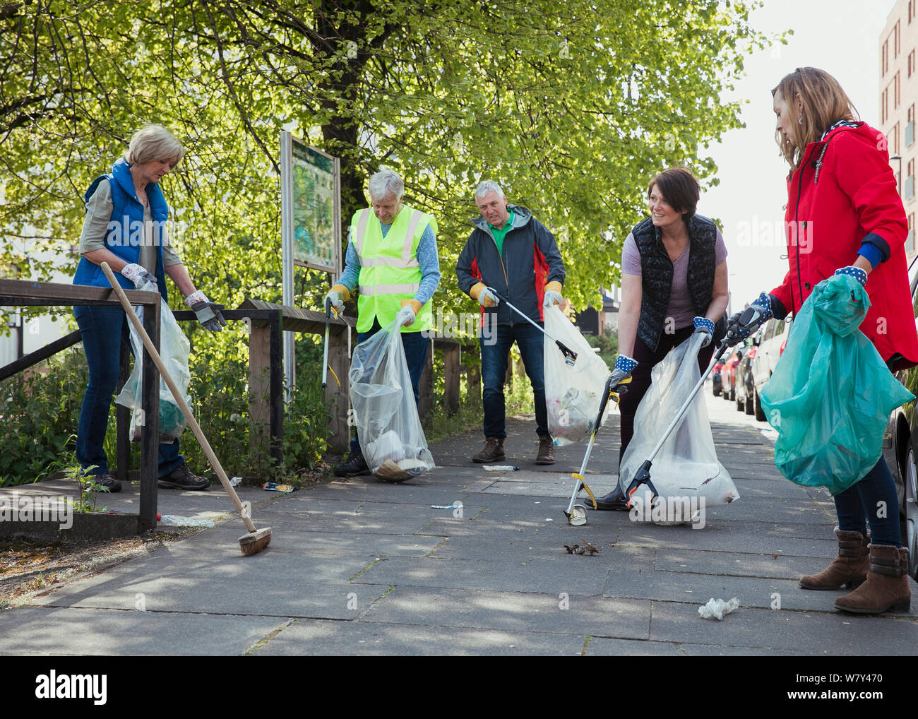 A group of five people participating in a city clean-up together. Stock Photo