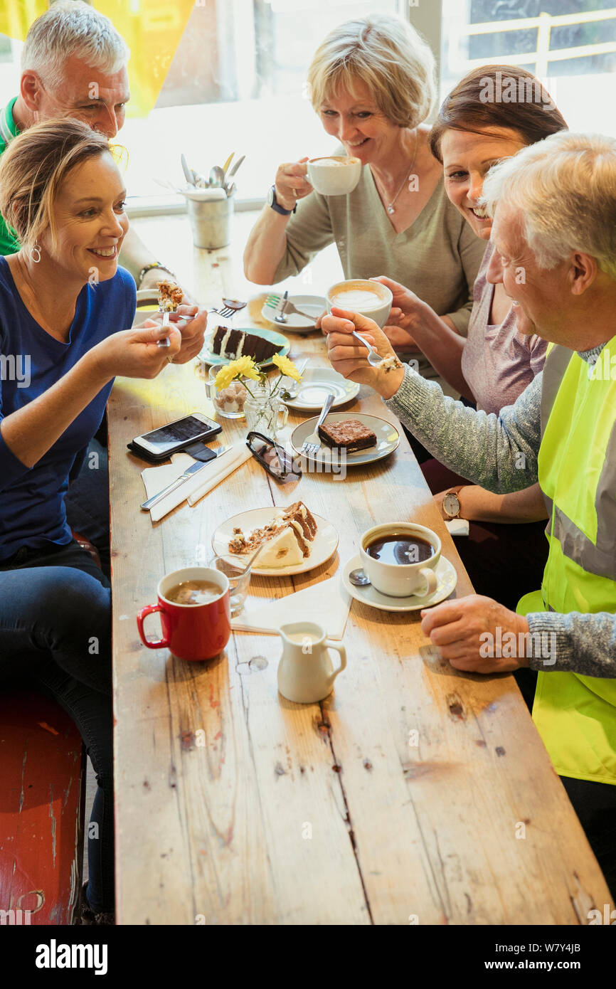 A group of five people taking a break from city cleaning and having coffee and cake. Stock Photo
