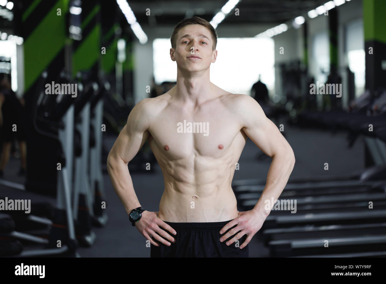 Portrait of sportsman with perfect body standing at the gym after