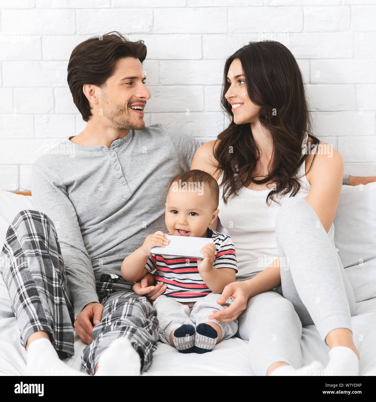 Little baby licking modern cellphone of dad, sitting with happy parents  Stock Photo - Alamy