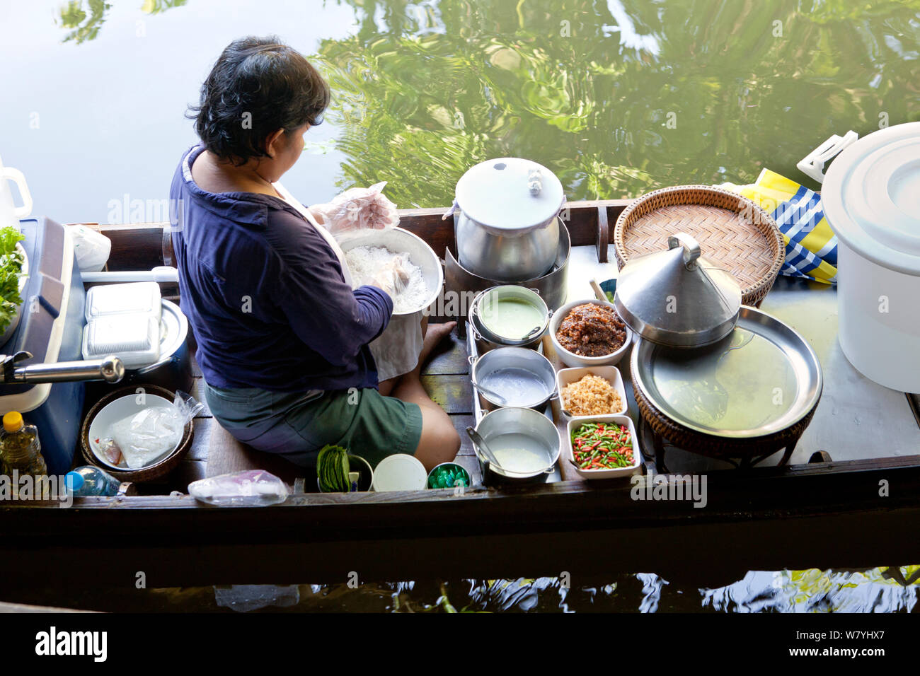 Woman preparing food in boat at the Ladmayom Floating Market near Bangkok. Thailand, September 2014. Stock Photo