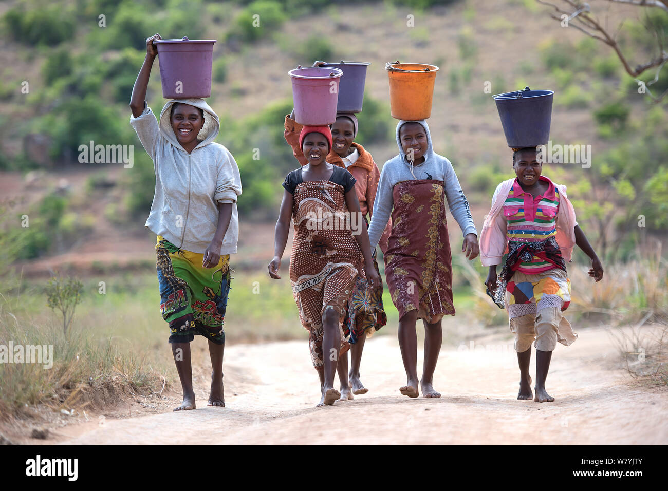 Woman carrying buckets of water on the head, coming back from the well, Anjaha Community Conservation Site, near Ambalavao, Madagascar. November 2014. Stock Photo