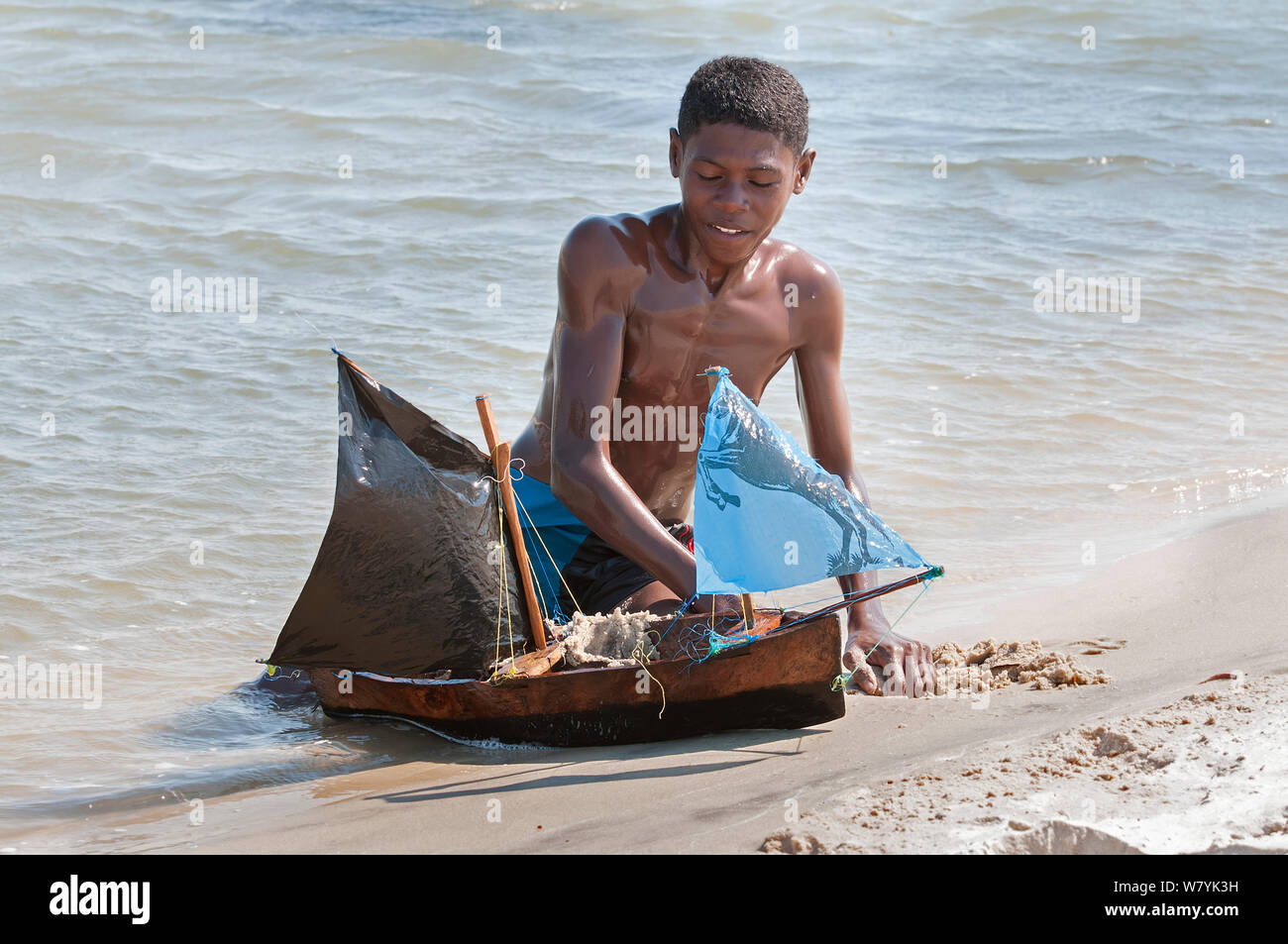 Young Vezo boy, playing with toy boat (pirogue) Morondave, Madagascar. November 2014. Stock Photo