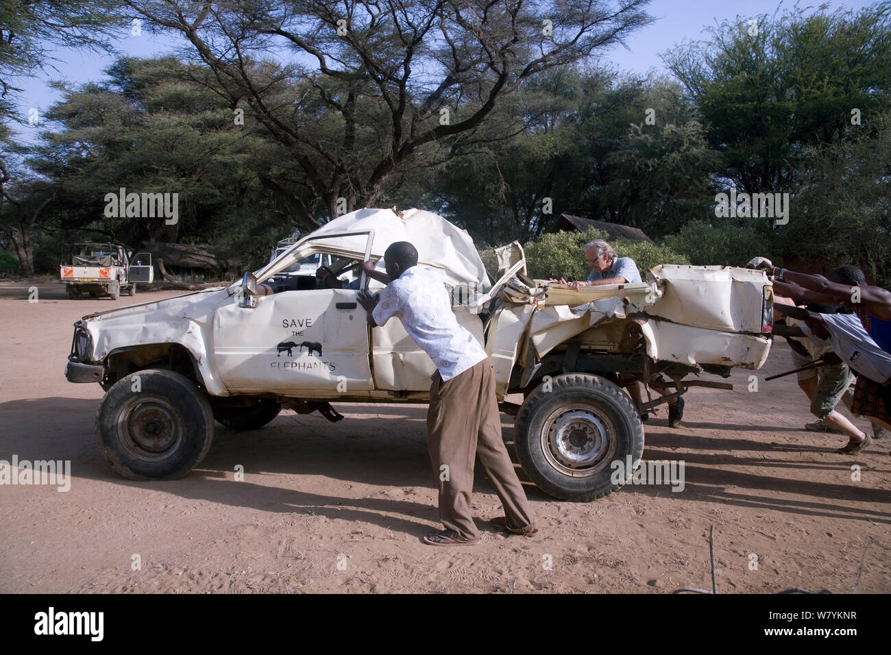 Former Save the Elephants research vehicle destroyed by bull elephant in Samburu National Reserve, Kenya. Save the Elephants workers including Iain Douglas-Hamilton trying to push start the LandCrusier. Model Released. Stock Photo