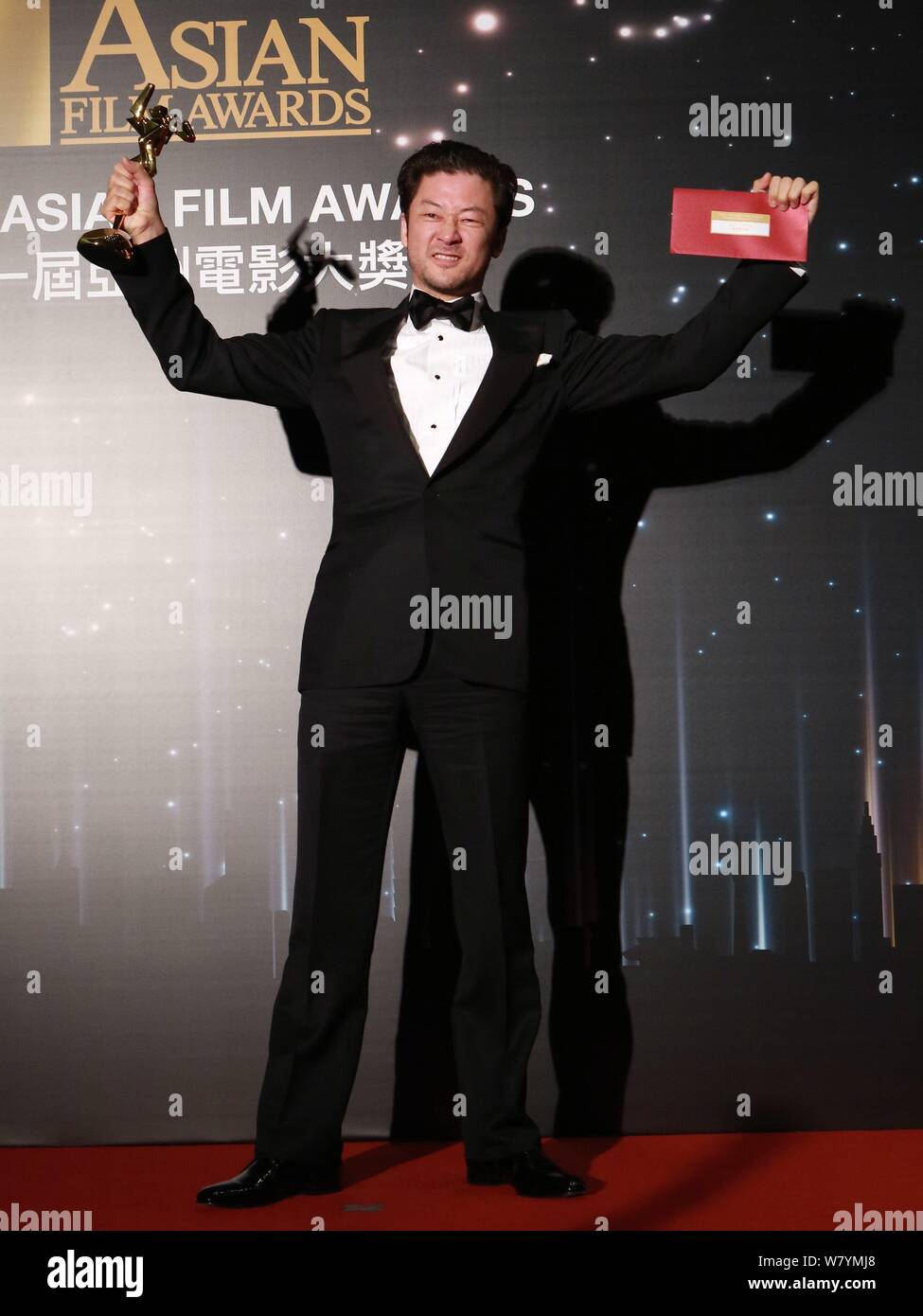Japanese actor Tadanobu Asano holds up his trophy after winning the