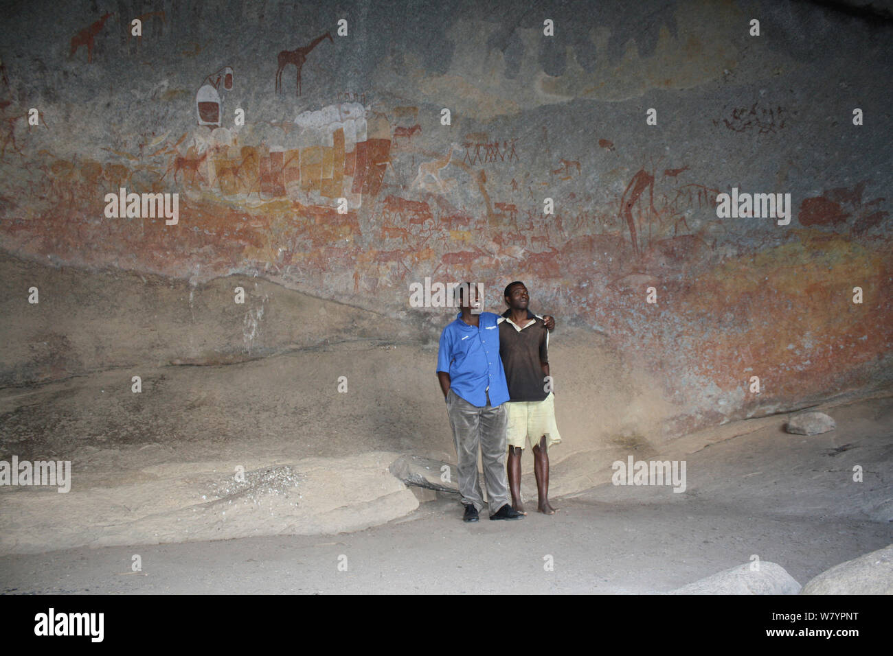 Park ranger and guide in front of San Rock paintings, Mtopo hills, Zimbabwe. January 2011. Stock Photo