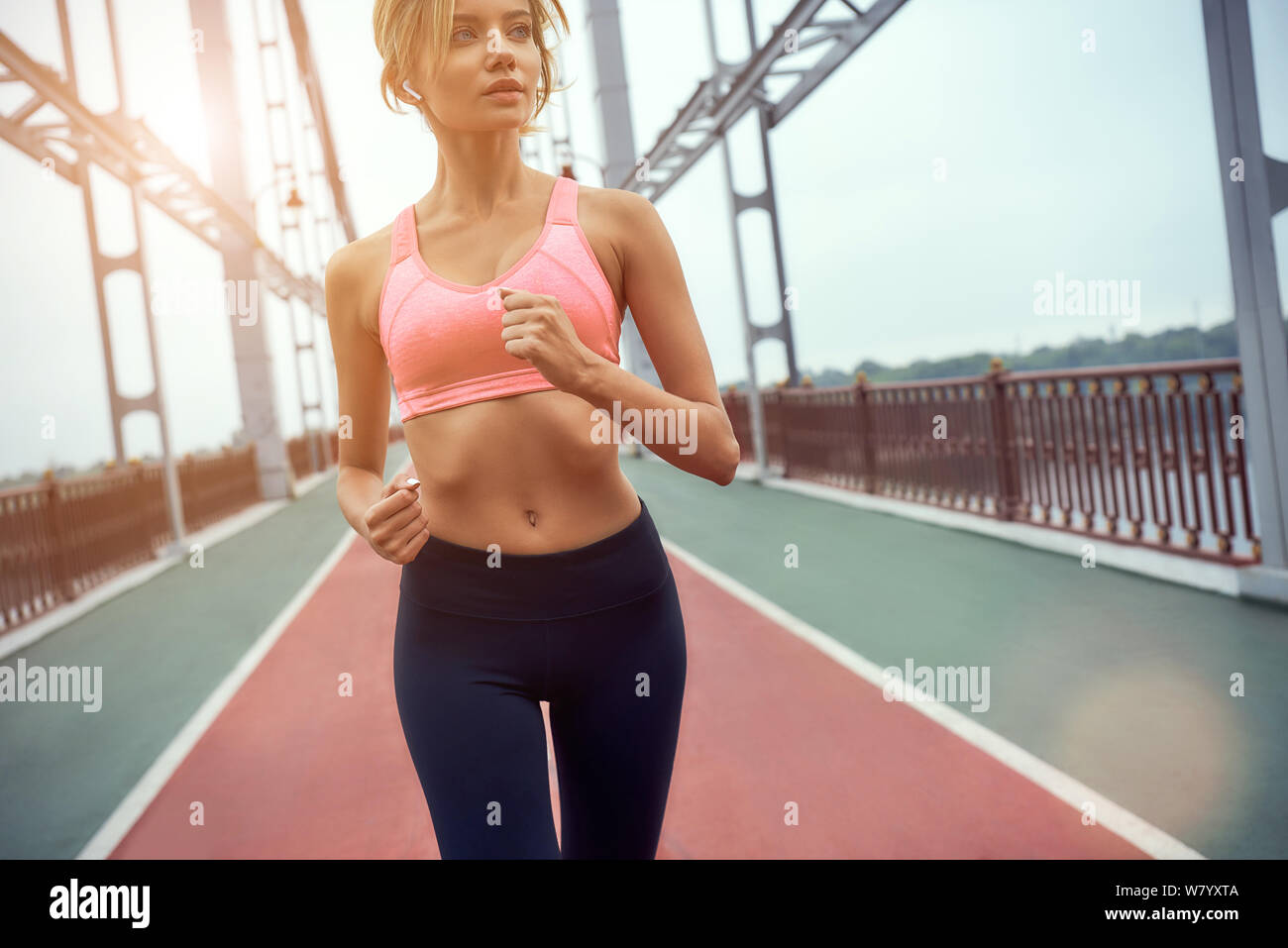 Never give up Young and beautiful blonde woman in sports clothing jogging on the bridge. Sport concept. Healthy lifestyle Stock Photo