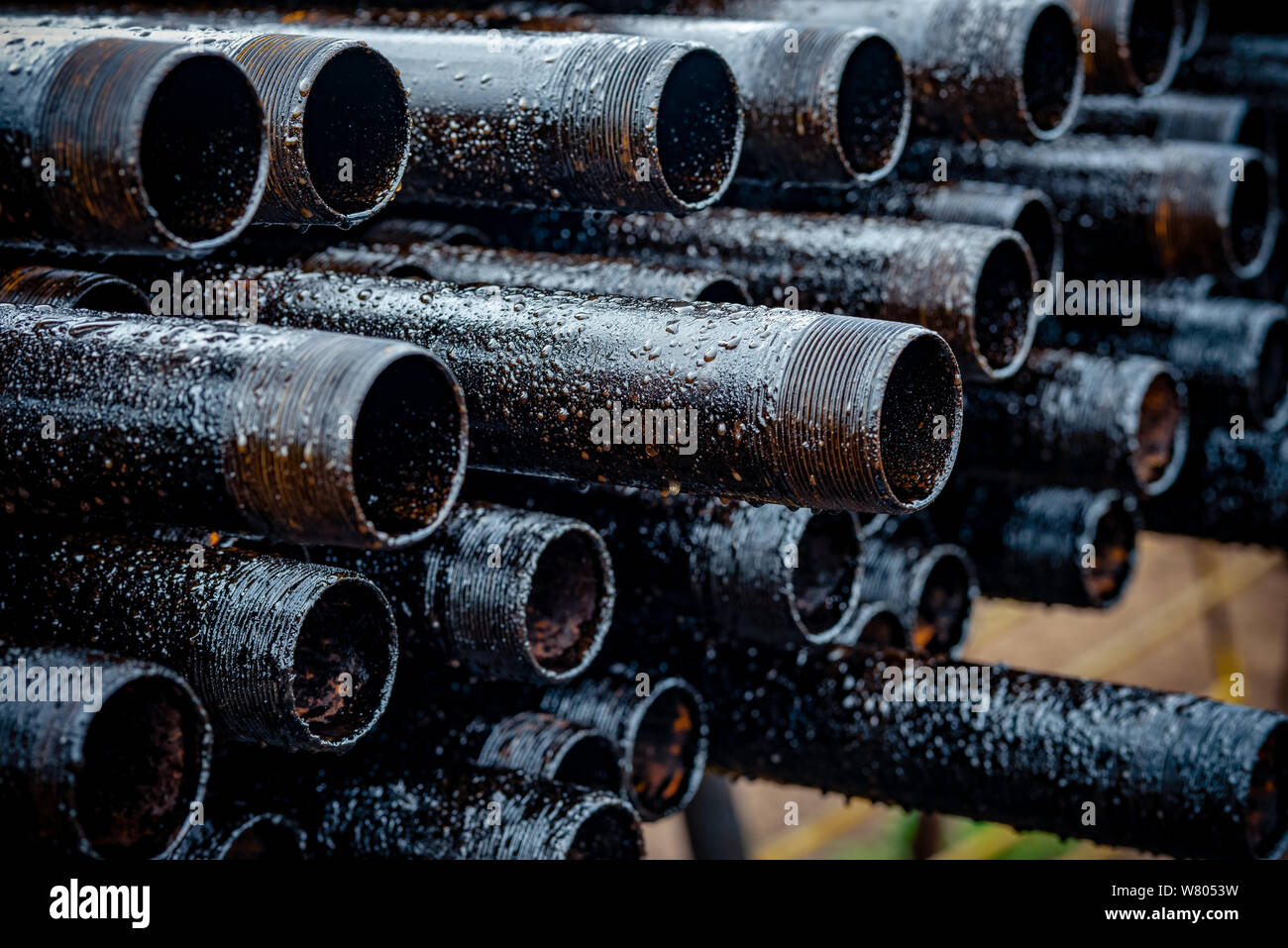 Oil Drill pipe. Rusty drill pipes were drilled in the well section. Downhole drilling rig. Laying the pipe on the deck. View of the shell of drill pip Stock Photo