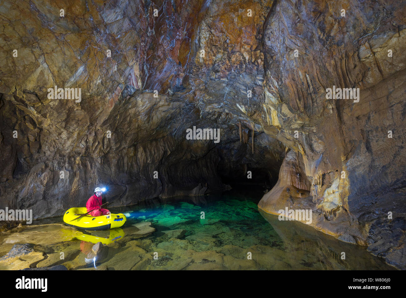 Man exploring underground lakes via rigid inflatable boat, Cross Cave (Krizna jama) under Cross Mountain, Green Karst, Slovenia, October 2014. Stock Photo