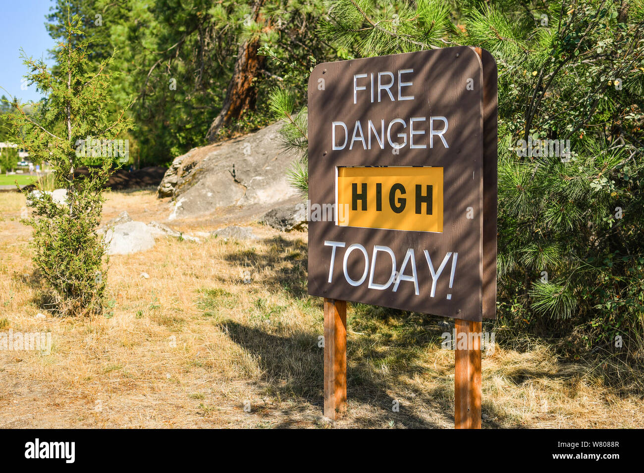 A sign posted on dry grass on public land alerting that fire danger is high today. Stock Photo