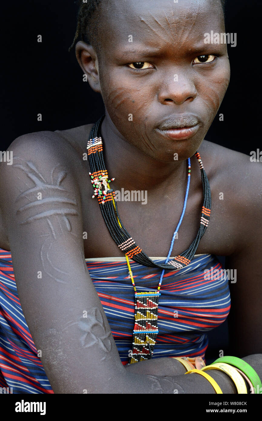 Young woman from the Toposa tribe displaying facial and skin scarification on arm and traditional jewels, Omo Valley, Ethiopia, March 2015. Stock Photo