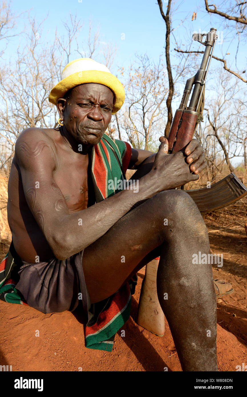 Older man from the Bodi tribe displaying elaborate skin scarifications, and holding Kalashnikov gun. The ones on his shoulder are for enemies he killed, the circles on the arm are for big game he hunted, Omo Valley, Ethiopia, March 2015. Stock Photo