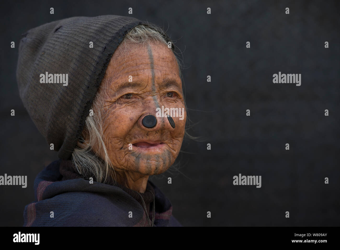 Apatani woman with facial tattoos and traditional nose plugs / Yapin Hulo made  to make them look unattractive to males from other tribes. These facial modifications are now outlawed. Apatani Tribe, Ziro Valley, Himalayan Foothills, Arunachal Pradesh.North East India, November 2014. Stock Photo