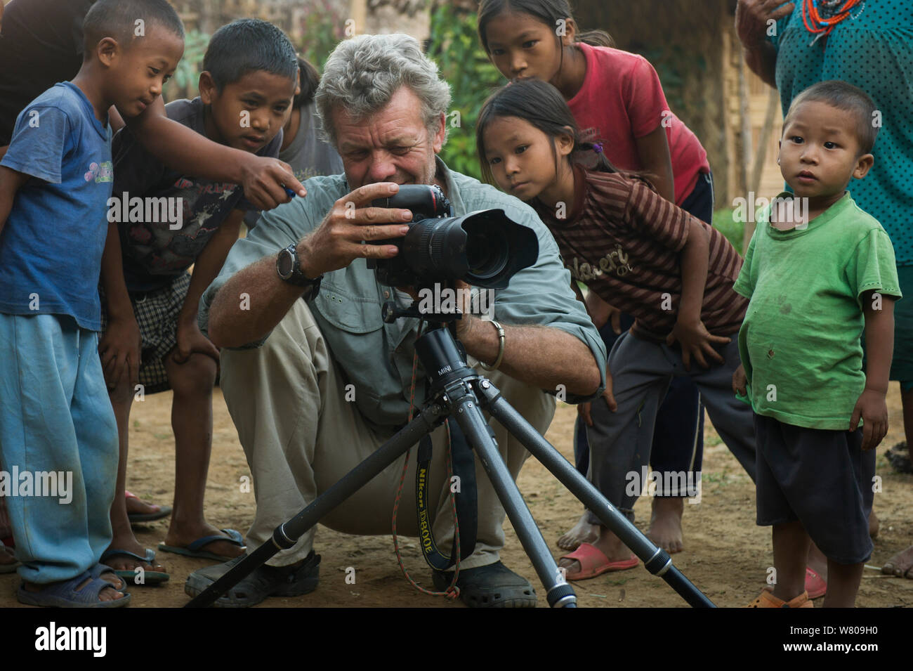 Photographer Pete Oxford with Naga head hunters children watching him take photos. Nagaland,  North East India, October 2014. Stock Photo