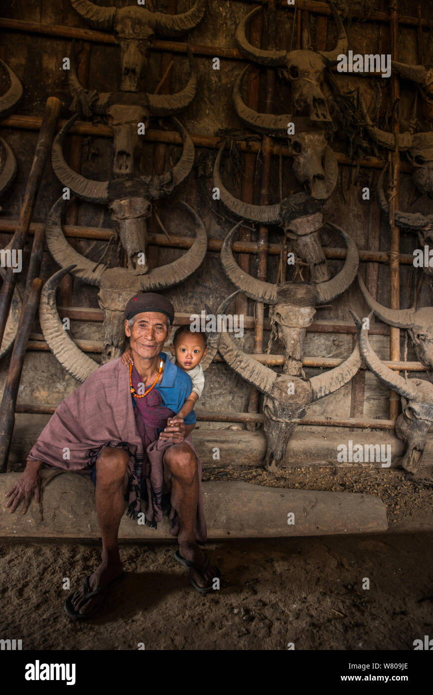 Konyak Naga man with grandson, in house decorated with buffalo skulls, Mon district, Nagaland, North East India, October 2014. Stock Photo