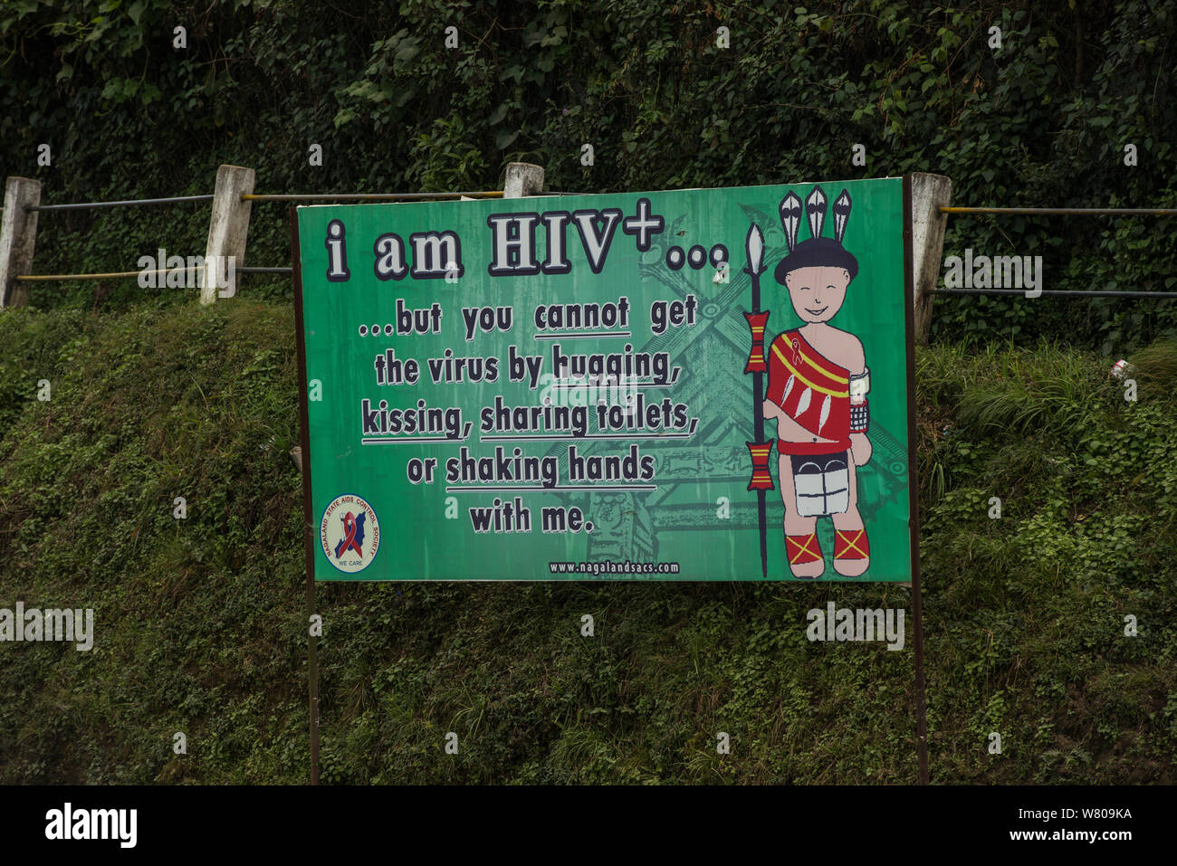 HIV signs awareness sign featuring Ao Naga headhunting tribesman in traditional festival clothing. Nagaland, North East India, October 2014. Stock Photo