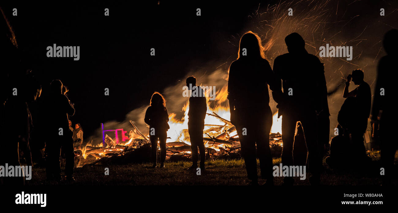 People warming up near campfire Stock Photo