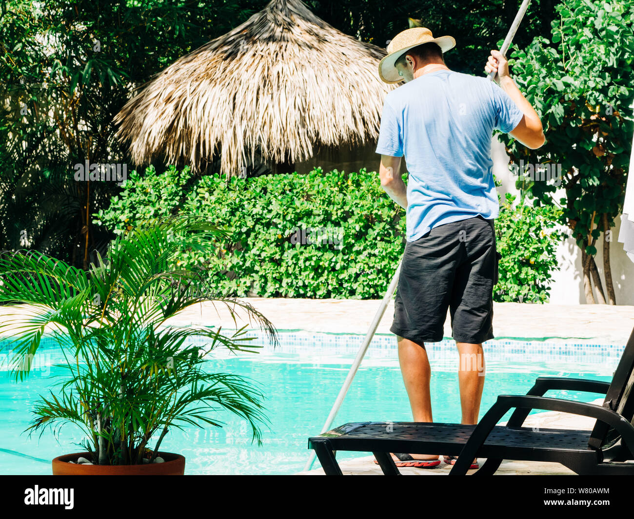 A man cleans a swimming pool outside Stock Photo Alamy