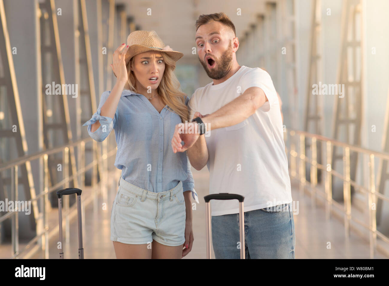 Late for flight. Couple checking time on watches Stock Photo