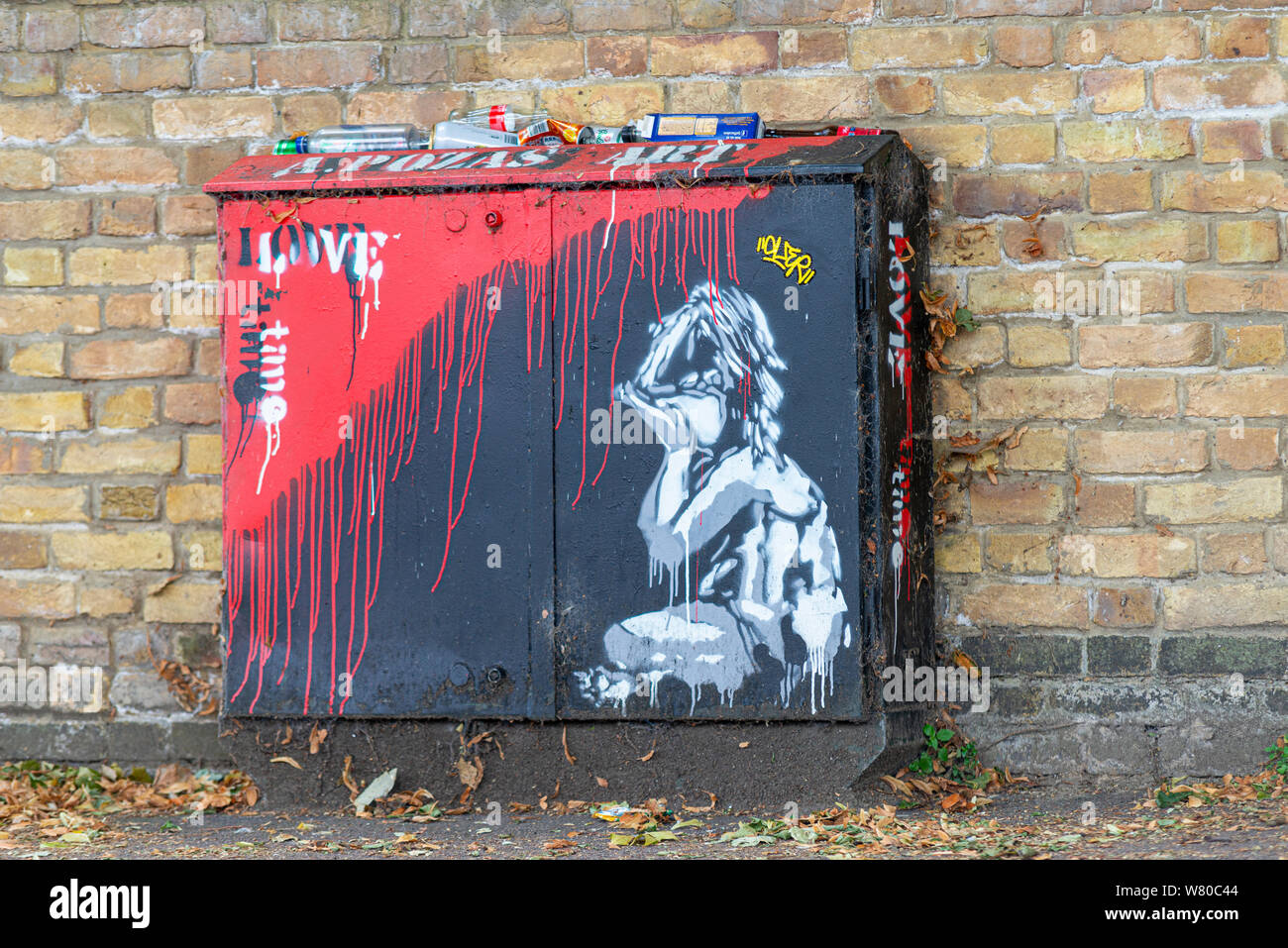 Banksy style artwork of a crying child on a telecommunications junction box, with red paint running down like blood and the words Love Time. Rubbish Stock Photo