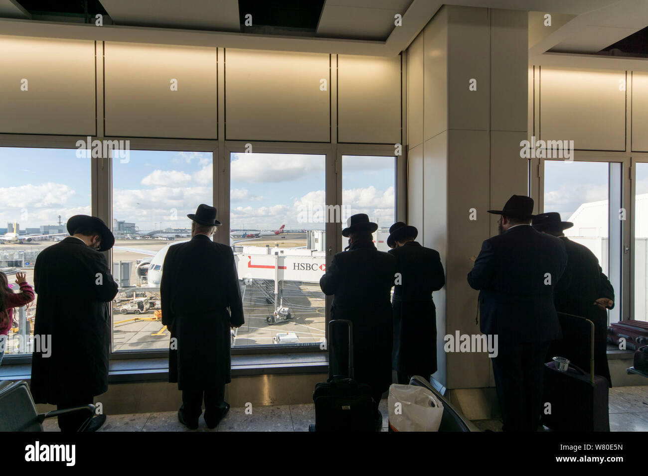 Heathrow Airport, London, United Kingdom. A group of Ultra-Orthodox ('Haredi') Jewish men pray while waiting for a flight. Stock Photo
