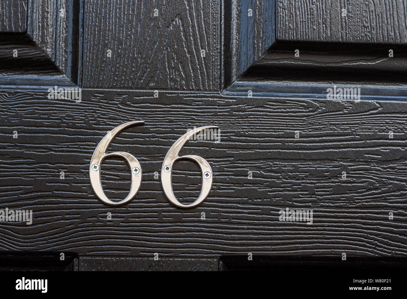 House number 66 on a shiny black door Stock Photo
