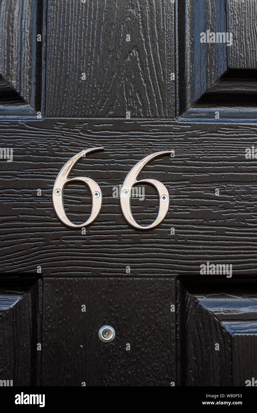 House number 66 on a shiny black door Stock Photo