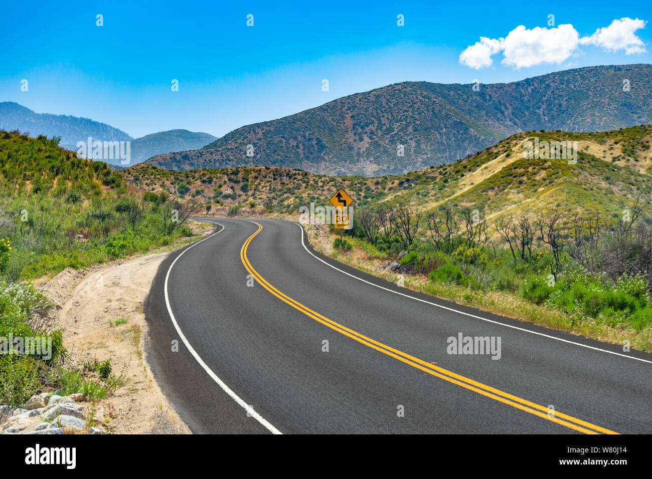 Curved mountain road with 30 MPH caution road sign Stock Photo