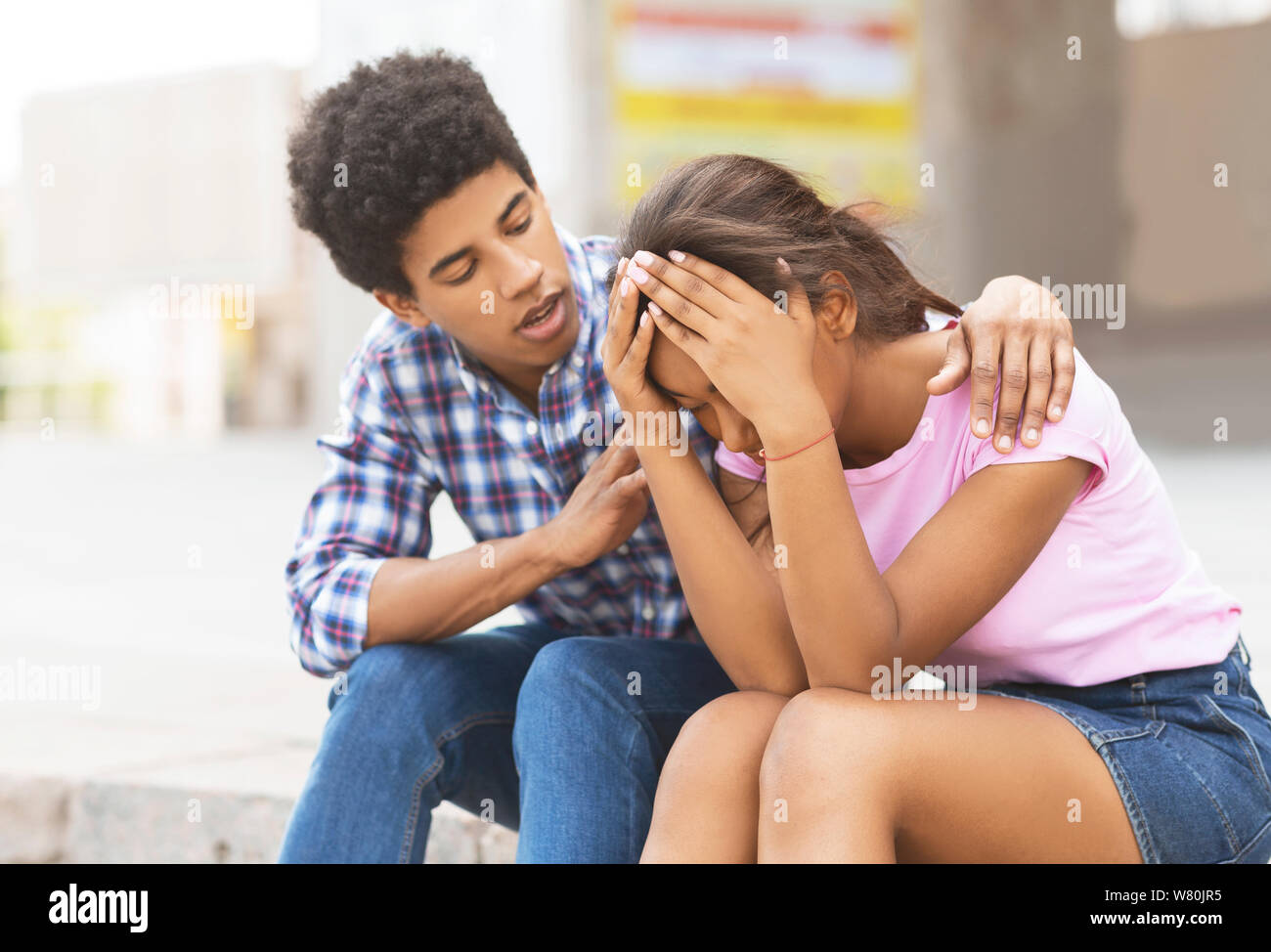 Young guy comforting his sad girlfriend that crying on public Stock Photo
